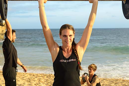 A pretty, fit girl lifts weights on the beach in Kauai for Physical Therapy